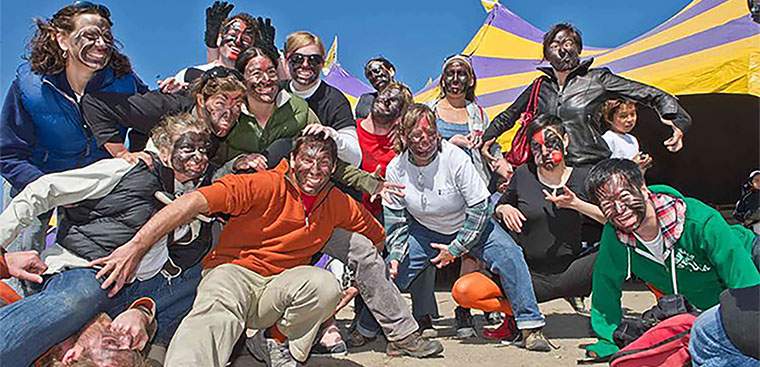 Photo of a group of people outside posing together with faces painted with Greenlandic masks.